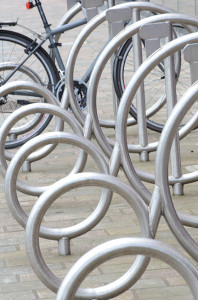 A series of metal circles that form a bike rack with one bike at the far end.