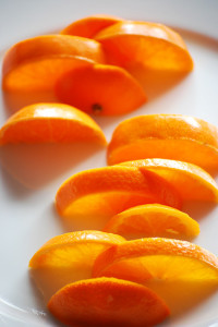 Half slices of orange arranged on a white plate so there are gaps between them