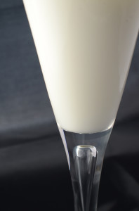 A fluted wine glass of milk against a balck and grey background