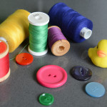 Still life of different coloured cottons and buttons with a small yellow duck
