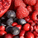 Close up of a bowl of berries - strawberries, raspeberries, pomegranate seeds and blueberries