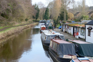 Looking down a river with canal boats moored along the right hand side