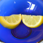 Two half slices of lemon in a bright blue glass bowl