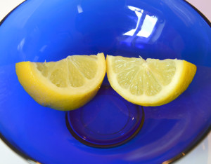 Two half slices of lemon in a bright blue glass bowl