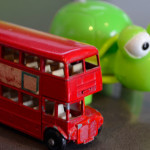Toy double decker bus beside a bright green wind up tortoise
